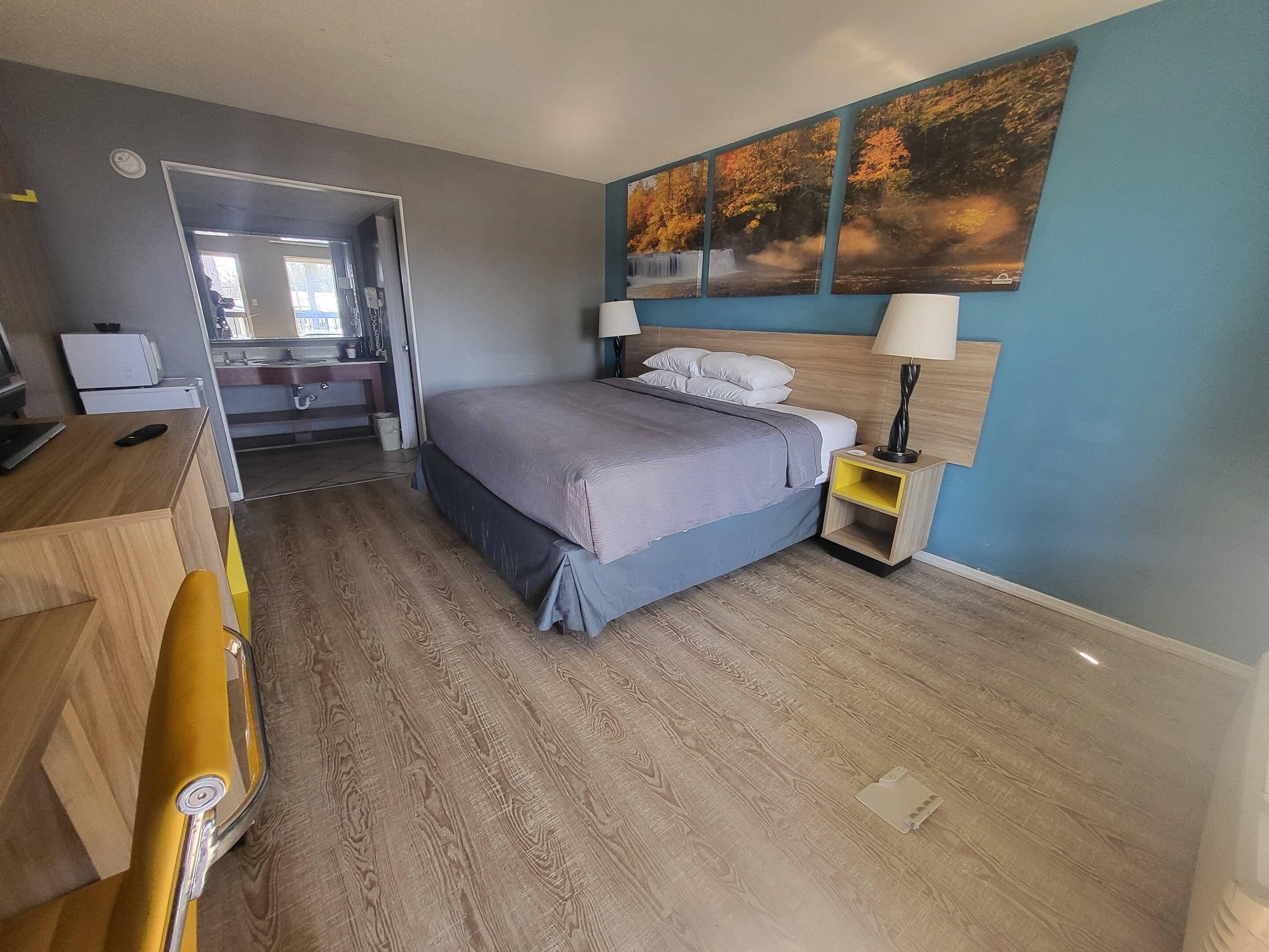 A bedroom with a bed, bedside tables, a desk, and a mirror.