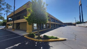 A multi-story parking garage with a clear sky, a tree in the foreground, and a Shell gas station sign in the background. - Park Inn by Radisson, Attalla-Gadsden (Attalla)