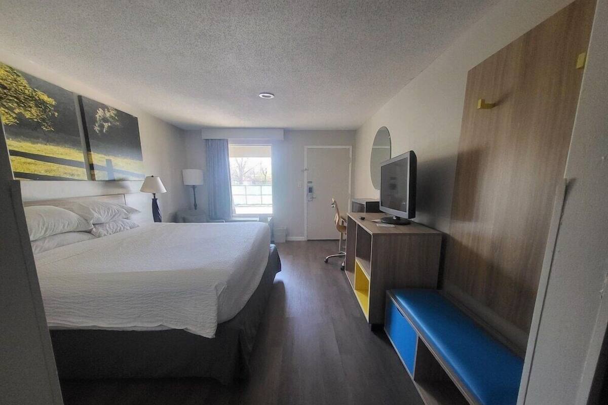 A hotel room with a bed, a desk with a computer, a television, and a window.