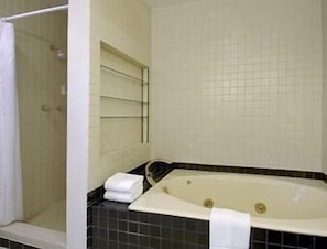 Bathroom features a large bathtub, shower area with glass door, and tiled walls.
