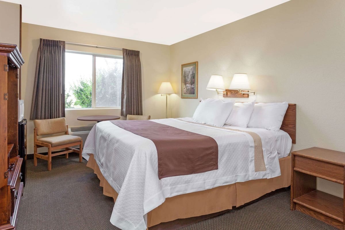 Een hotelkamer met een bed, een stoel, een bureau en een lamp.