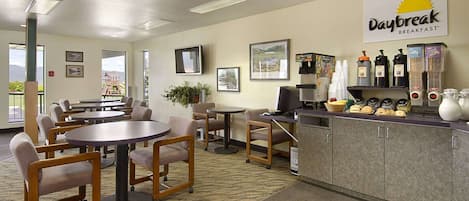 A Daybreak breakfast restaurant with tables and chairs, a coffee station, and framed pictures on the walls.