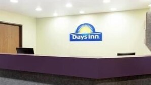Un mostrador de recepción con el logotipo de Days Inn, una puerta de madera y un televisor de pantalla plana.