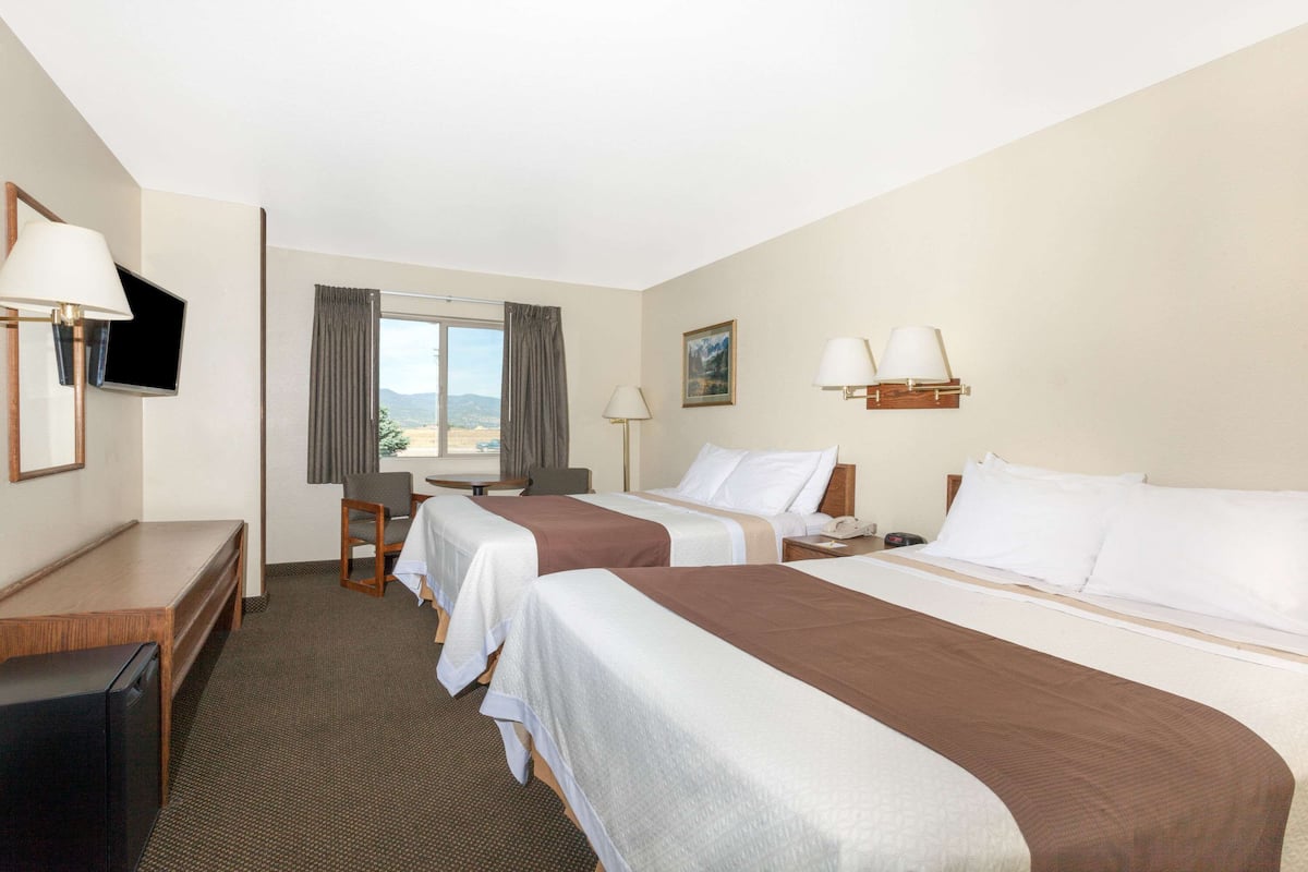 Een hotelkamer met twee bedden, een bureau, een televisietoestel en een raam met uitzicht.