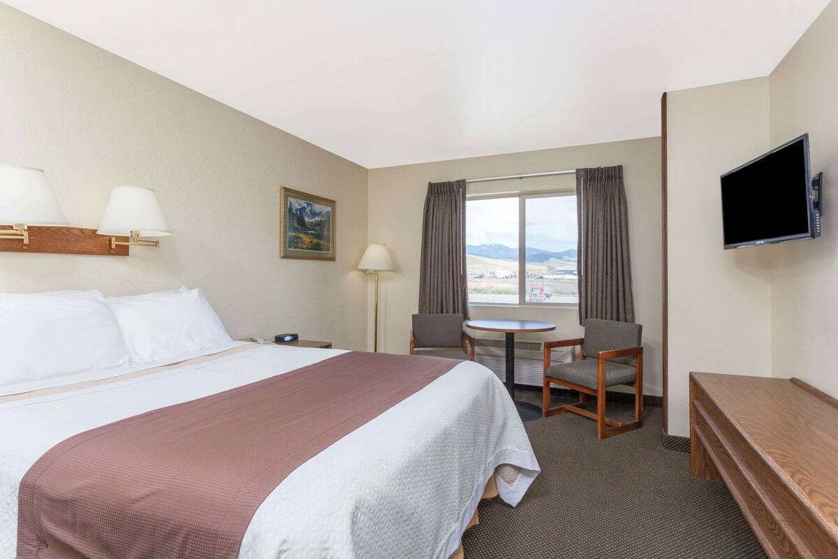 Een hotelkamer met een groot bed, een bureau, een stoel, een televisie en een raam met uitzicht.