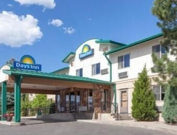 Welcome to Days Inn, featuring a simple entrance with a green awning and lush surroundings.