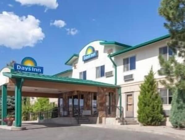 Welcome to Days Inn, featuring a simple entrance with a green awning and lush surroundings.