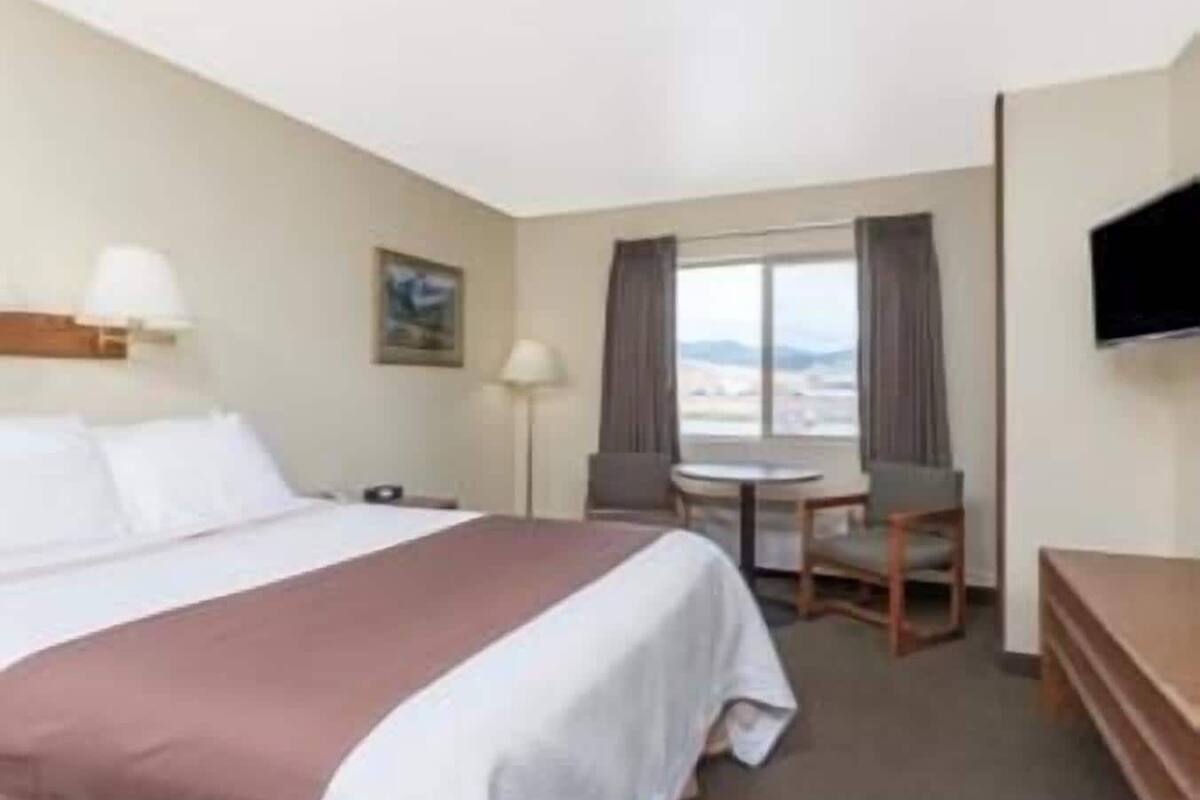 Een hotelkamer met een bed, bureau, stoel, televisie en raam met uitzicht.