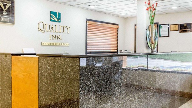 A reception area with a marble counter, a logo for 'Quality Inn' by Choice Hotels, and a framed award on the wall.