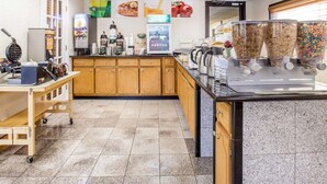 A breakfast bar with waffle maker, coffee machine, and cereal dispensers.