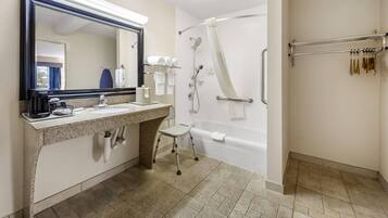 A bathroom with a sink, mirror, towel rack, shower, and a grab bar.