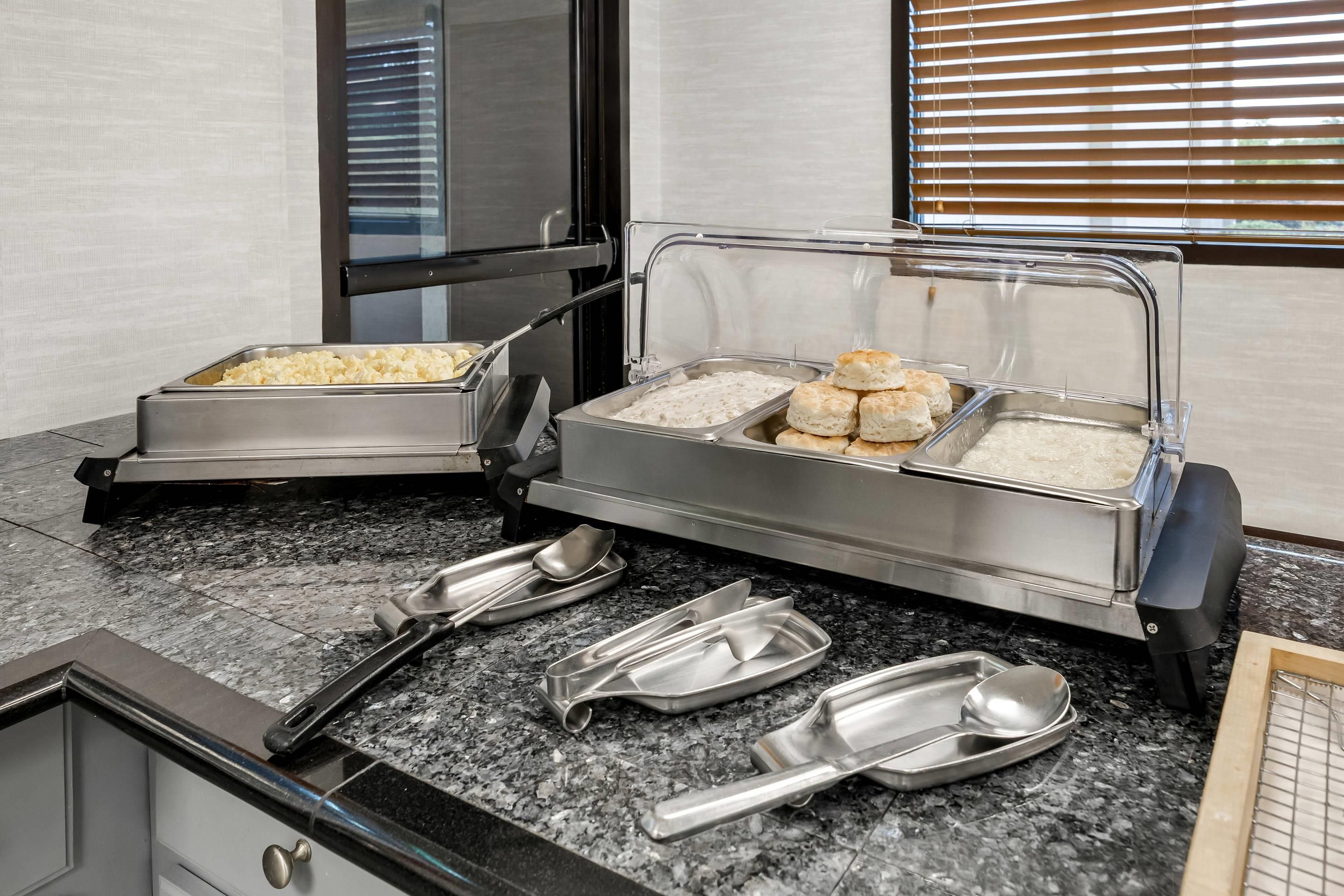 A buffet setup with various food items and serving utensils.