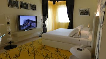 Ein Hotelzimmer mit Bett, Fernseher, Schreibtisch und einem dekorativen Teppich.