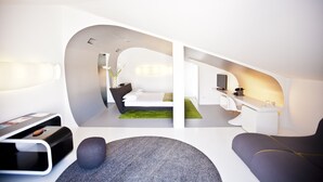 Un dormitorio moderno de planta abierta con cama, escritorio y zona de estar.