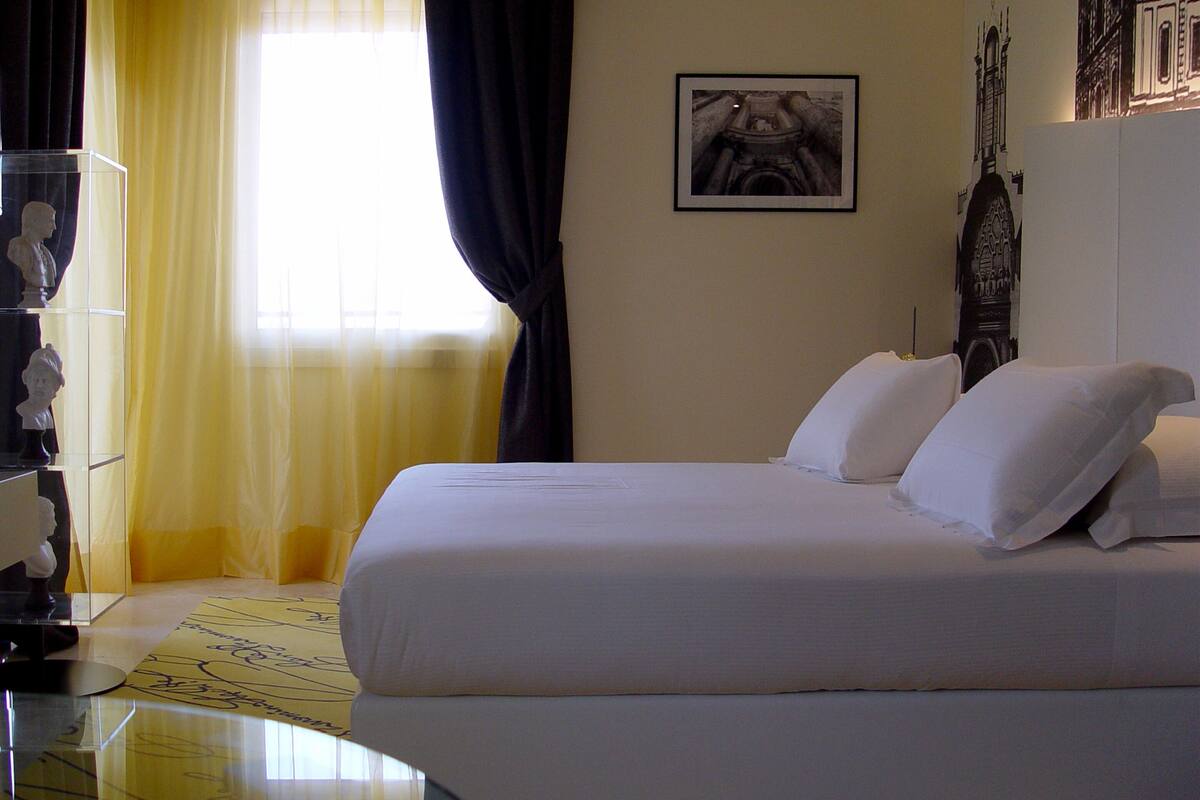 Una habitación de hotel con cama, escritorio y ventana con cortinas.