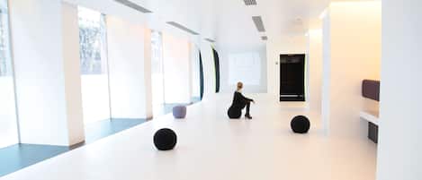 A spacious, modern interior with large windows, a minimalist design, and a person performing.