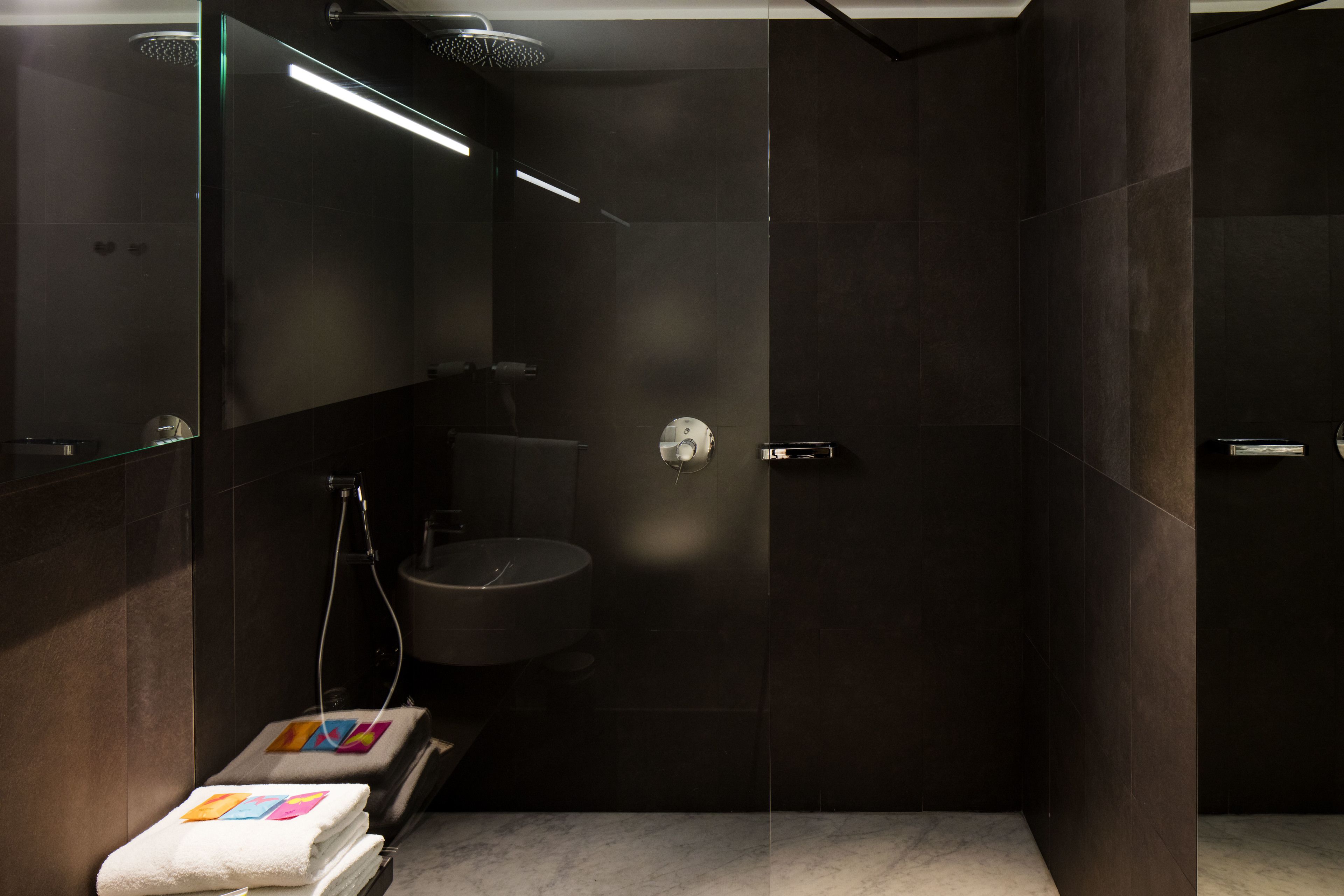 A modern bathroom with a glass-enclosed shower, a round sink, and a mirror.
