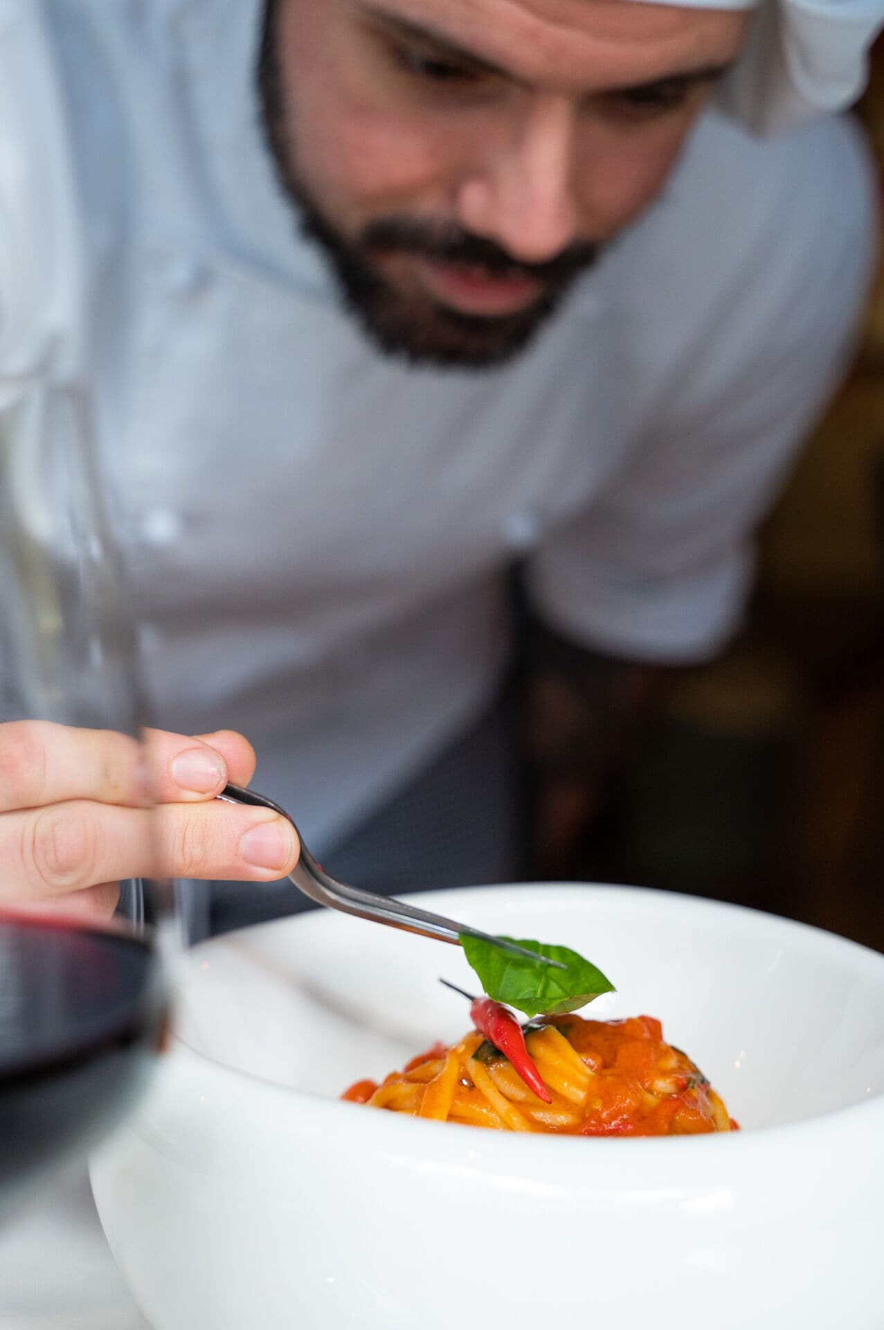 Un chef sosteniendo un tenedor con un plato de pasta.