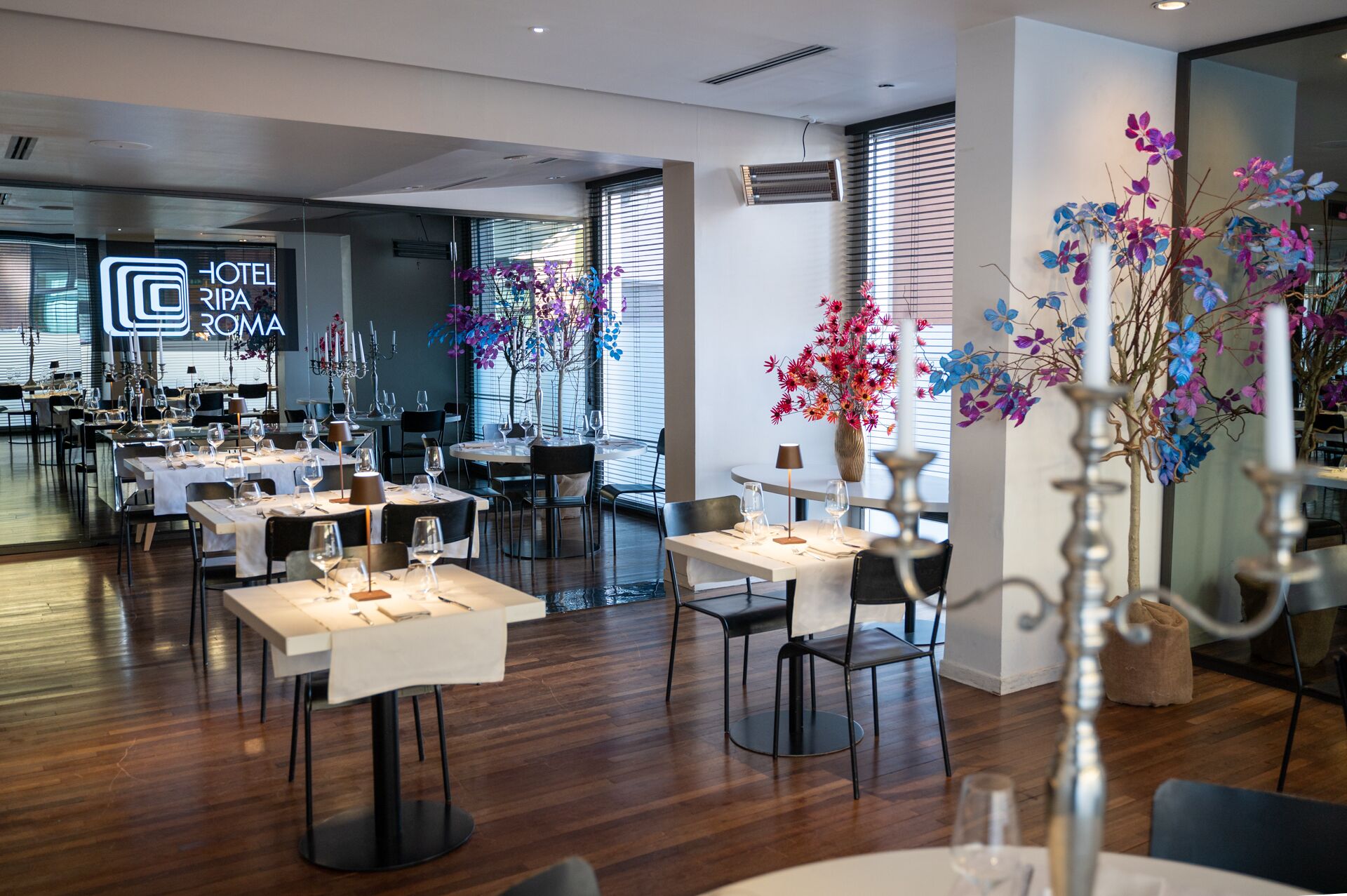A modern hotel restaurant with multiple tables set for dining, featuring a clean and contemporary interior design.