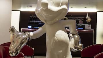Una gran escultura blanca de un personaje de caricatura en un vestíbulo con sillas rojas y un mostrador de recepción al fondo.