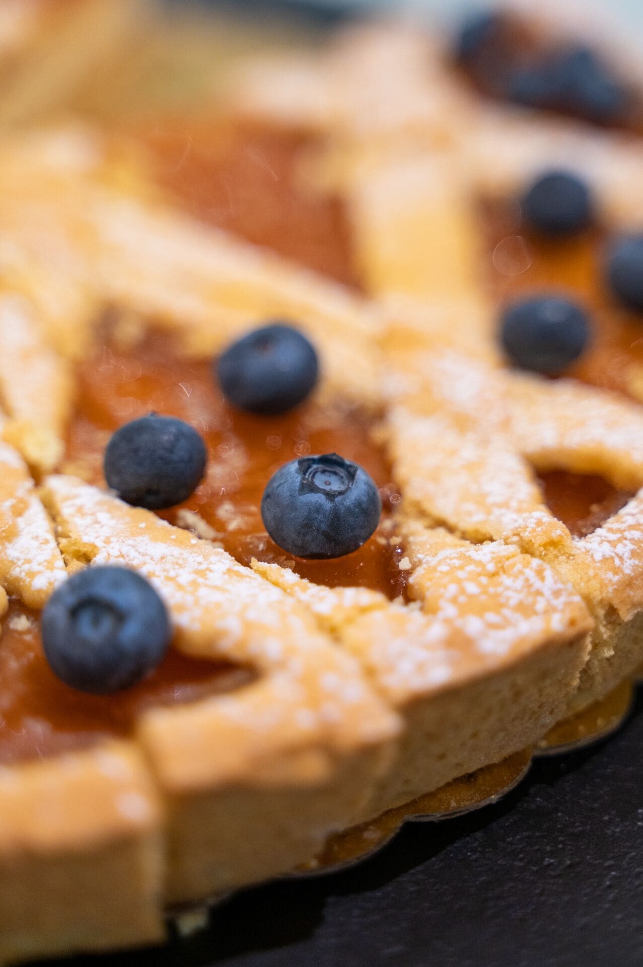 A close-up of a blueberry-topped pie with a lattice crust.