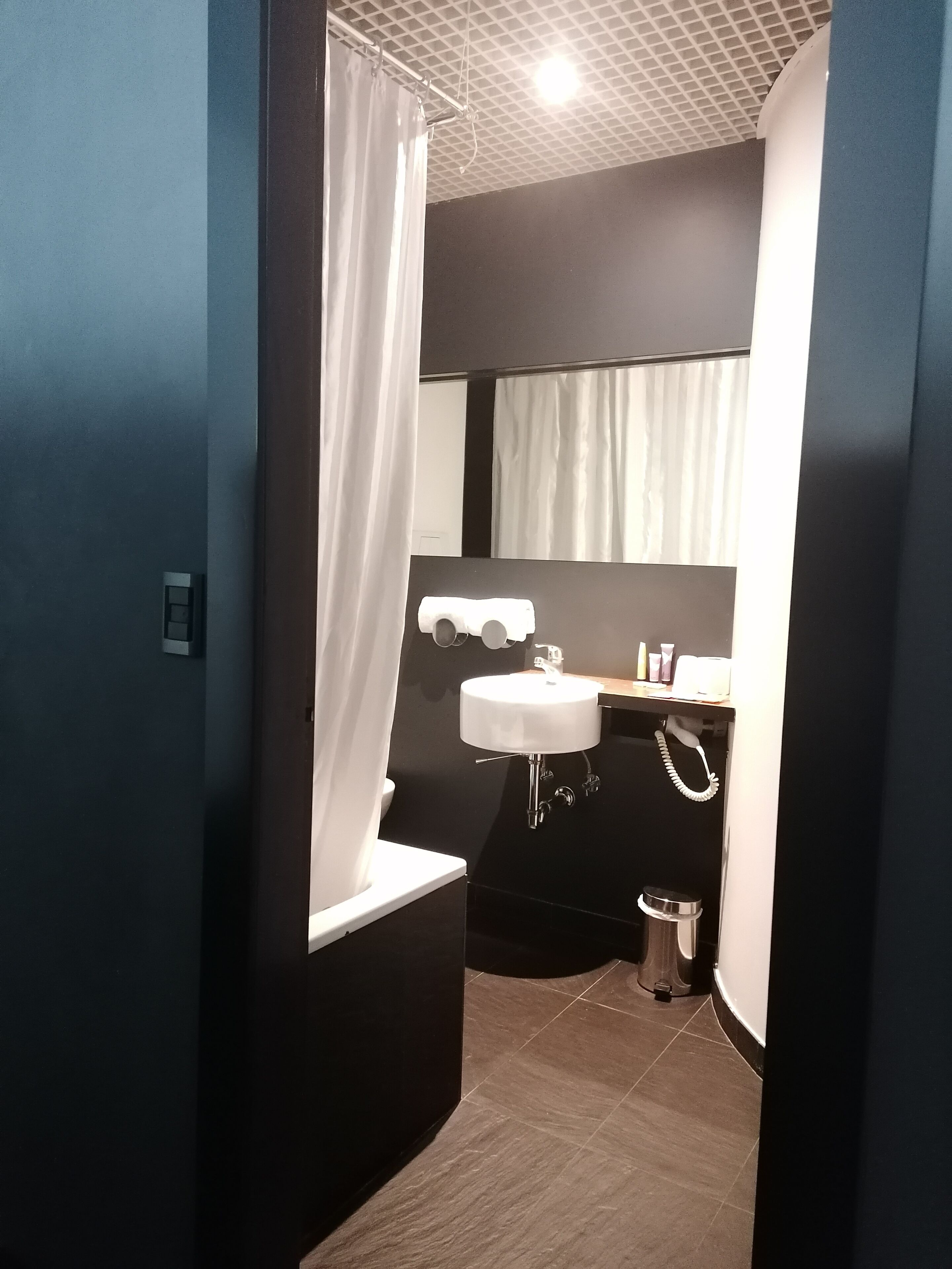 A modern bathroom with a white sink, a mirror, and a shower curtain.