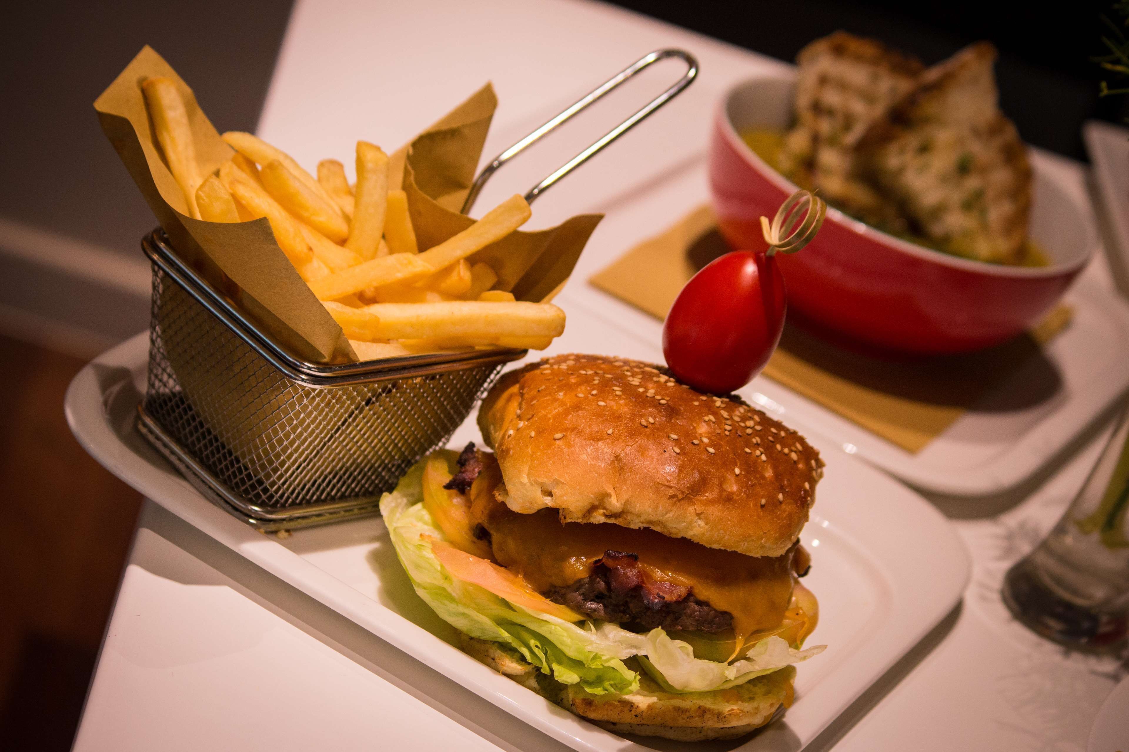 Eine Mahlzeit bestehend aus einem Burger, Pommes und einer Salat-Schüssel.