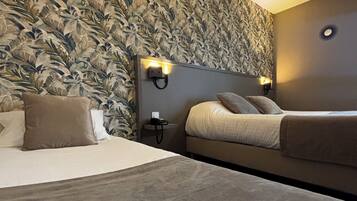 A hotel room with a large bed, a smaller bed, a nightstand, and a wall with a leafy pattern.