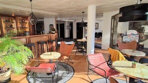 A hotel lobby with a bar area, seating arrangements, and a large potted plant.