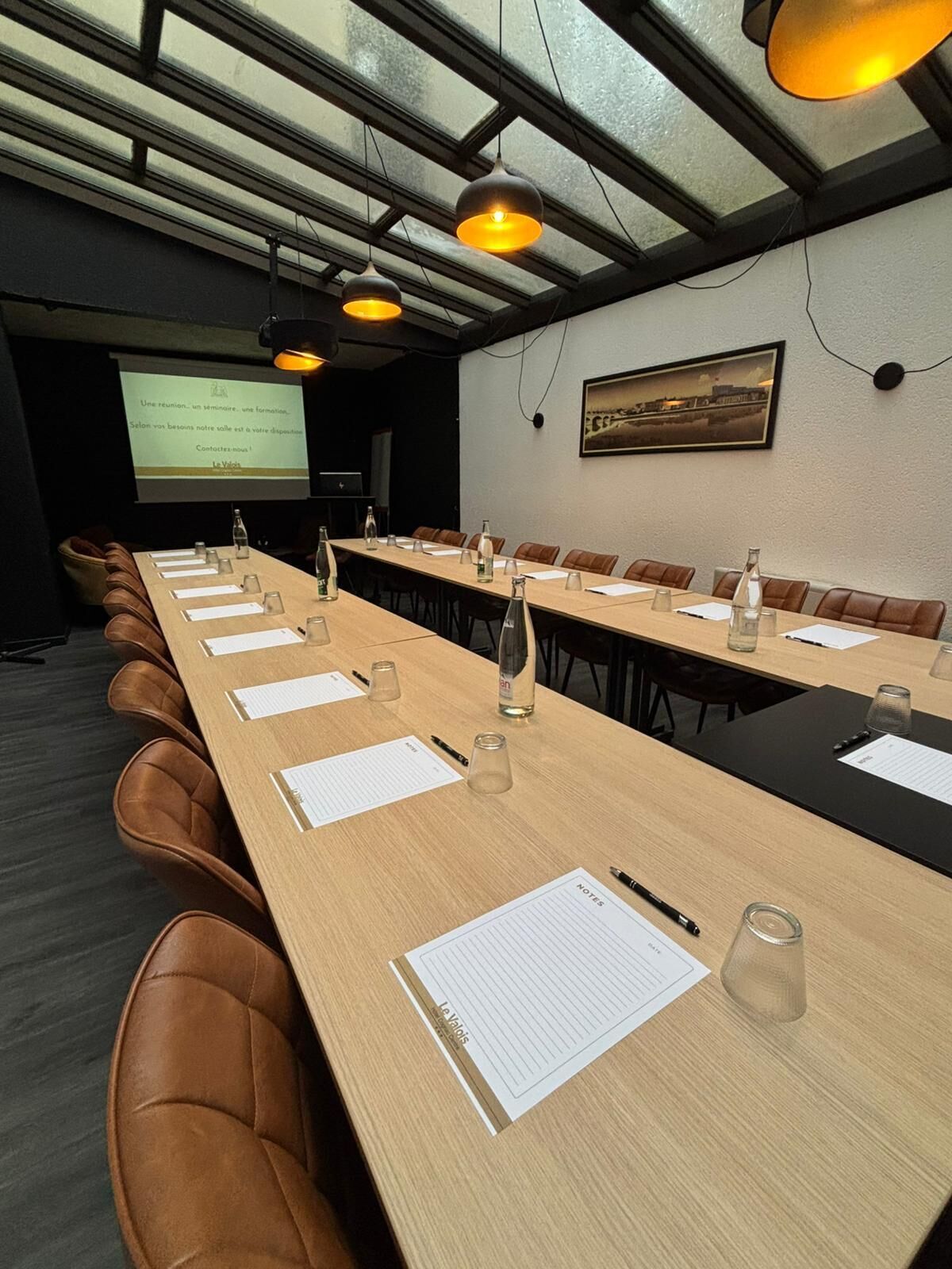 A conference room with a long table, leather chairs, and overhead lighting.