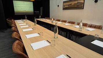 A conference room with a long table, leather chairs, and overhead lighting.