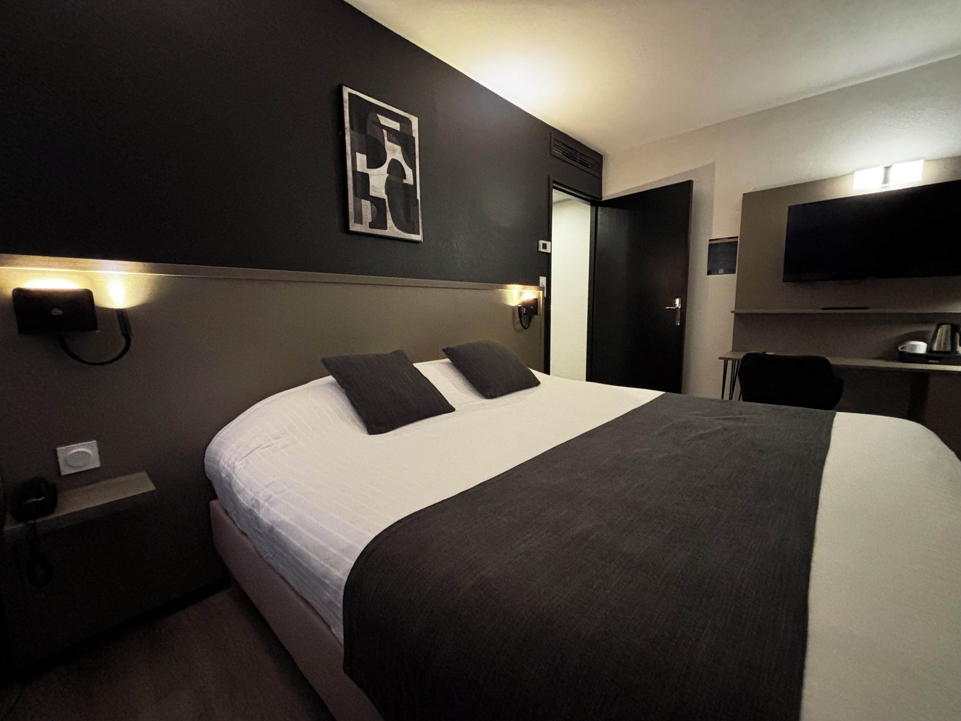 A hotel room with a large bed, a desk, and a TV.