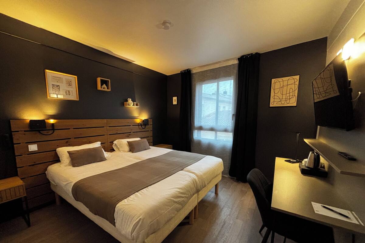 A hotel room with a large bed, bedside tables, a desk, and a chair.