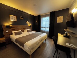 Ein Hotelzimmer mit einem großen Bett, Nachttischen, einem Schreibtisch und einem Stuhl.