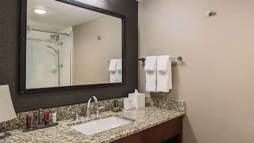 Une salle de bain avec un comptoir en granit, un lavabo, un miroir et un porte-serviettes.