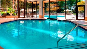 An indoor swimming pool with clear blue water, surrounded by lounge chairs and potted plants. - Sonesta Nashville Airport (Nashville)