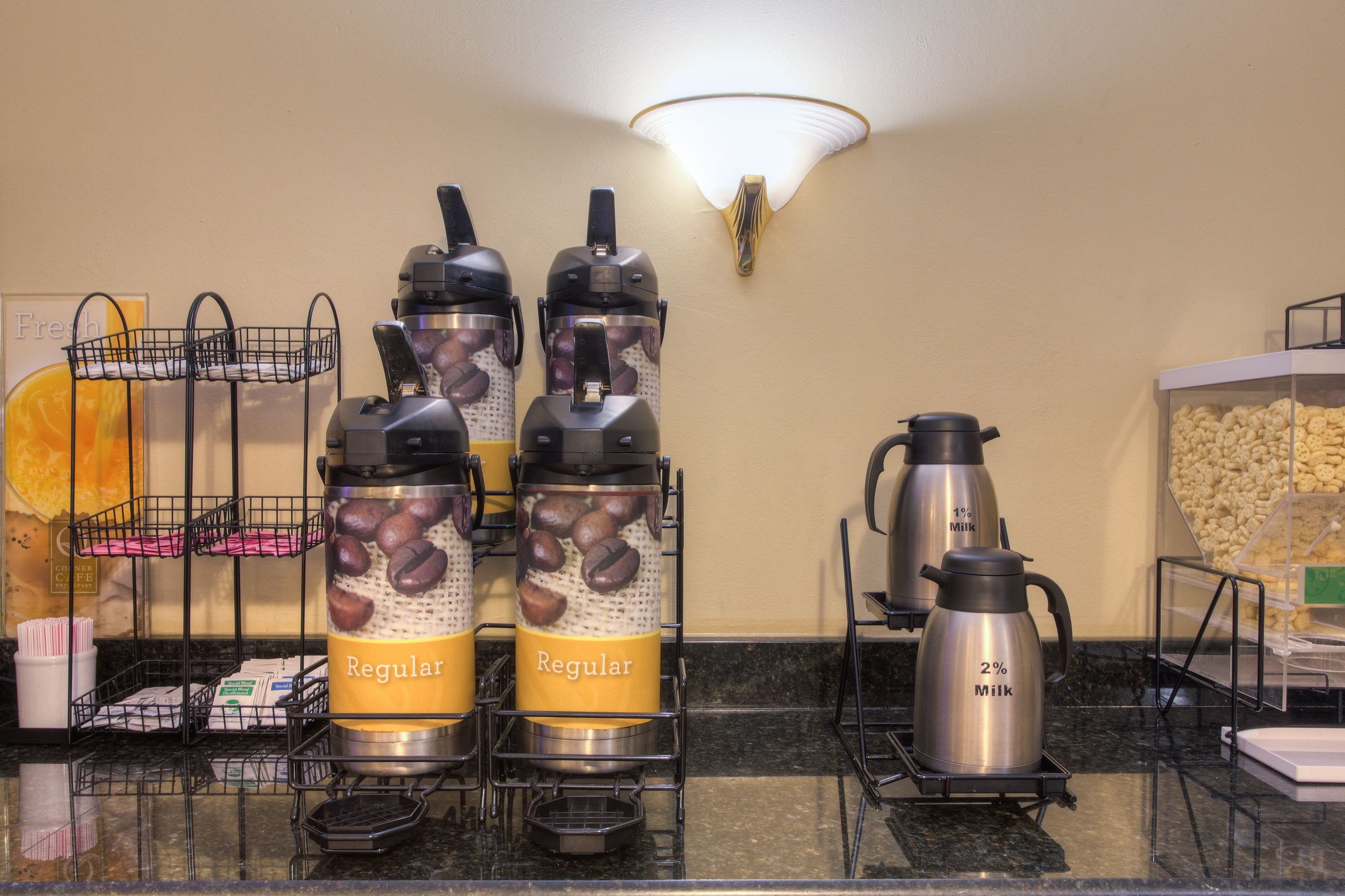 A coffee station with four coffee dispensers labeled "Regular" and "Milk" in a hotel setting.