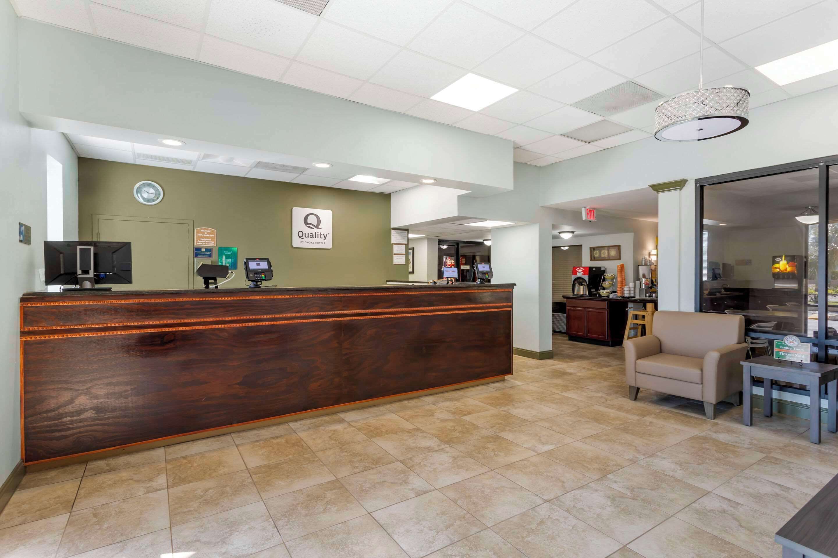 A reception area with a wooden reception desk, a clock, and a sign that says "Quality".