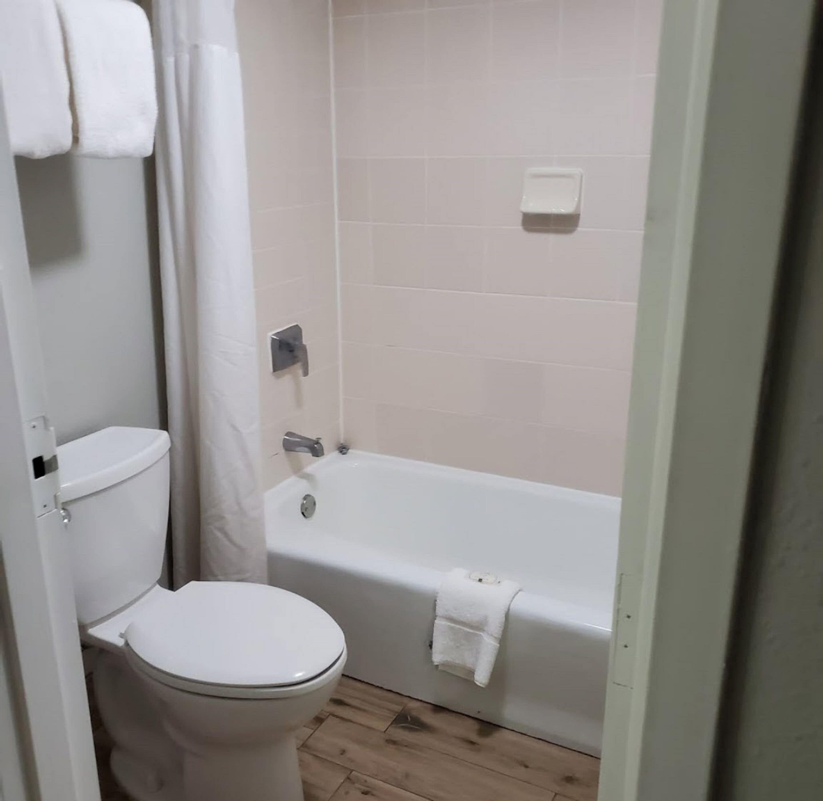 Un baño con inodoro, bañera y cortina de ducha.