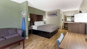 Una habitación de hotel con cama, escritorio, sillón, sofá y mesita de noche.