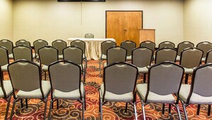 A conference room with rows of chairs, a table, and a projector screen. - Quality Suites Hickory South (Hickory)