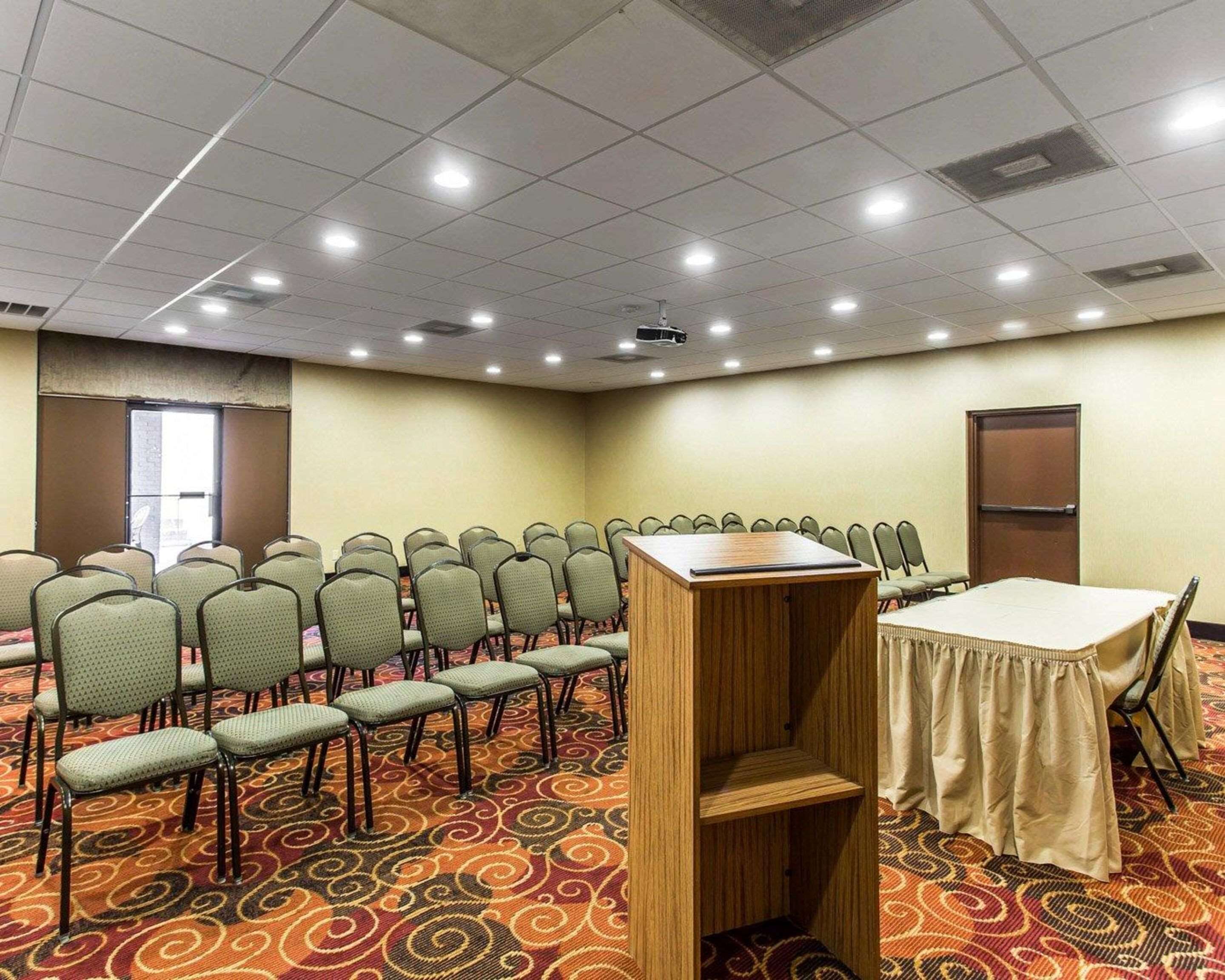 A conference room with rows of chairs, a podium, and a table.