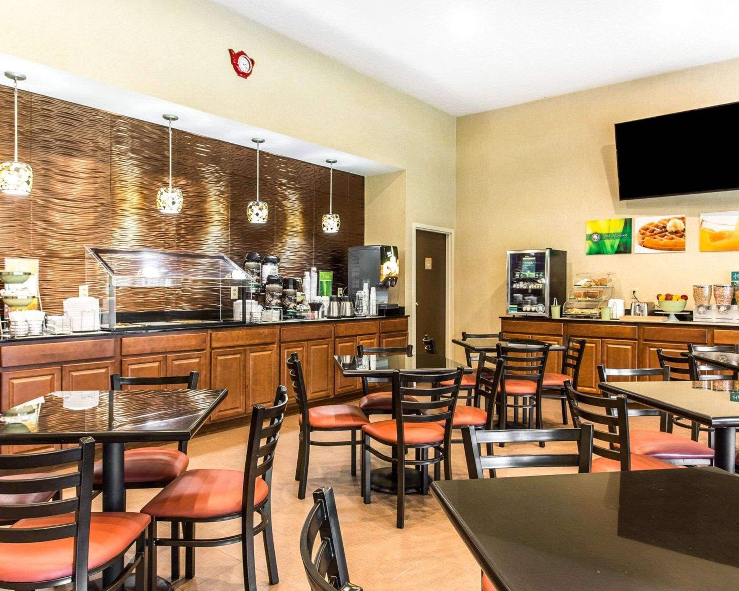 A hotel restaurant with wooden panel walls, hanging pendant lights, and a buffet counter with various food items.