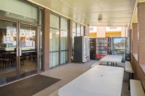Un restaurant avec des tables, un distributeur automatique et un réfrigérateur rempli de Coca-Cola.