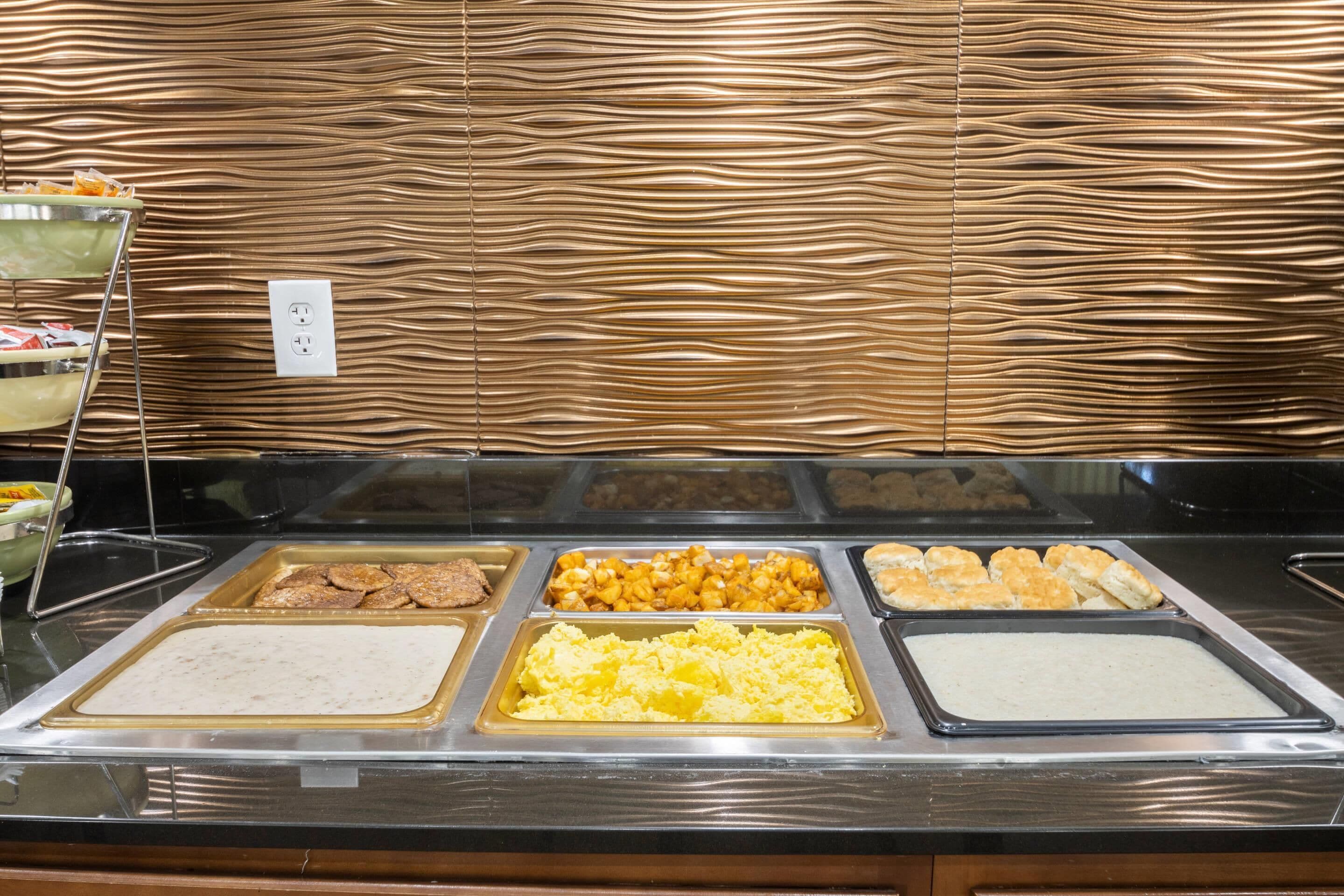 Een ontbijtbuffet met diverse gerechten, zoals roerei, ontbijtkoek en ander ontbijt.
