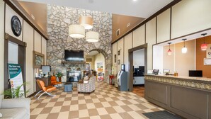A lobby with a checkered floor, stone wall, and a reception desk. - Quality Suites Hickory South (Hickory)