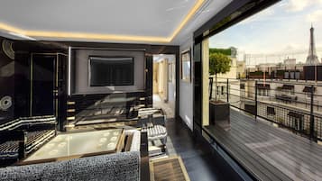 Een modern interieur met een grote flatscreen-tv, comfortabele zithoek en een balkon met uitzicht op de stad.