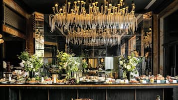 Ein luxuriöser Essbereich mit einem prächtigen Kronleuchter, mehreren floralen Tischdekorationen und einem reichhaltigen Buffet.