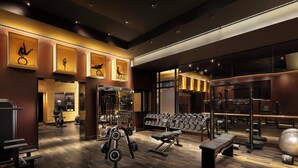 A modern gym with various exercise equipment, including dumbbells, a bench, and weight machines.