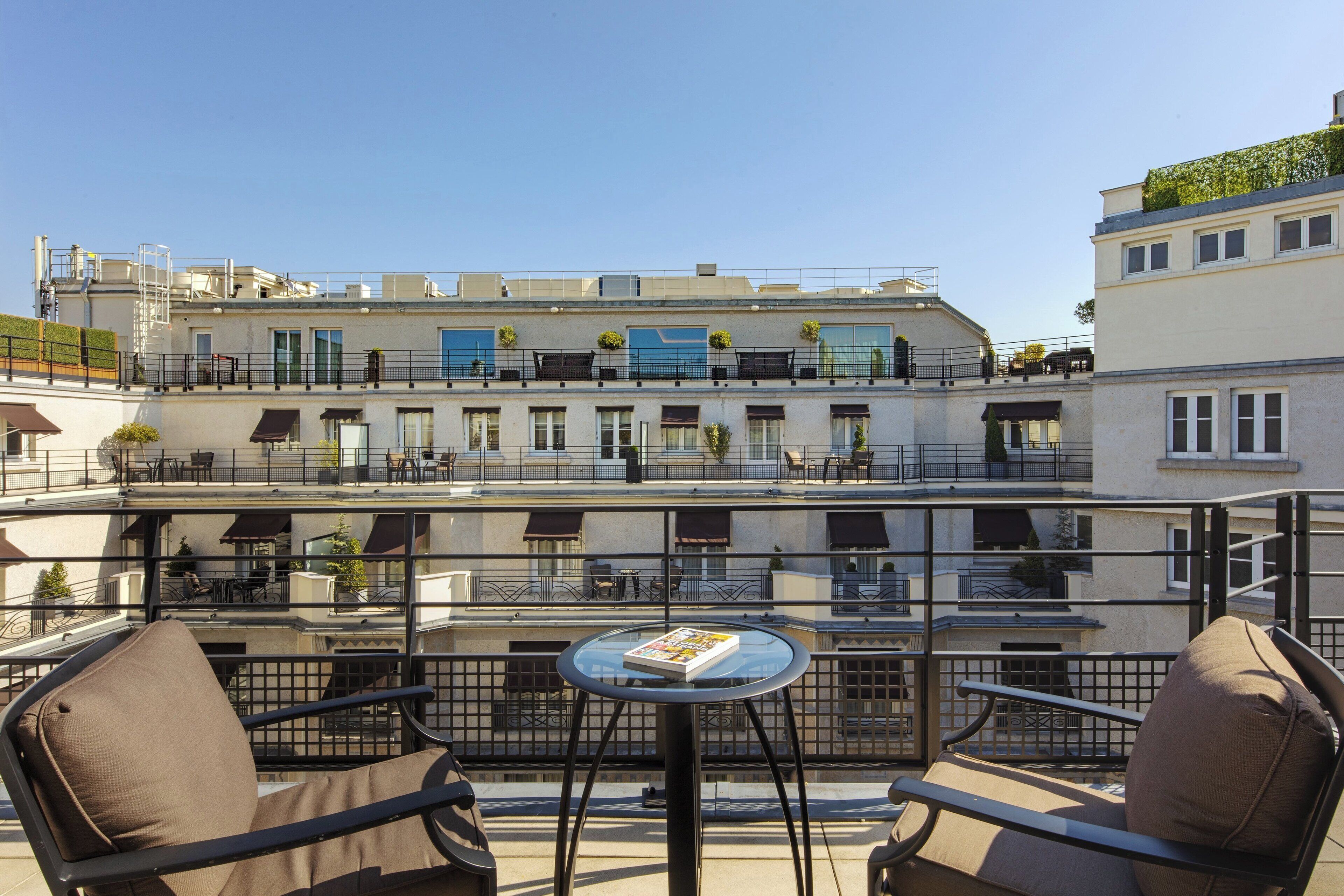 Une terrasse sur le toit, dotée d’un espace extérieur aménagé et offrant une vue sur un immeuble à plusieurs étages.